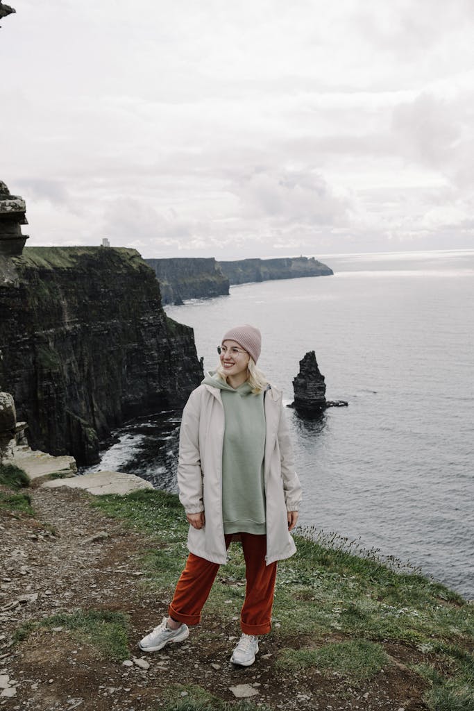 Woman standing near Cliffs of Moher, enjoying the view. Perfect for travel and tourism themes.